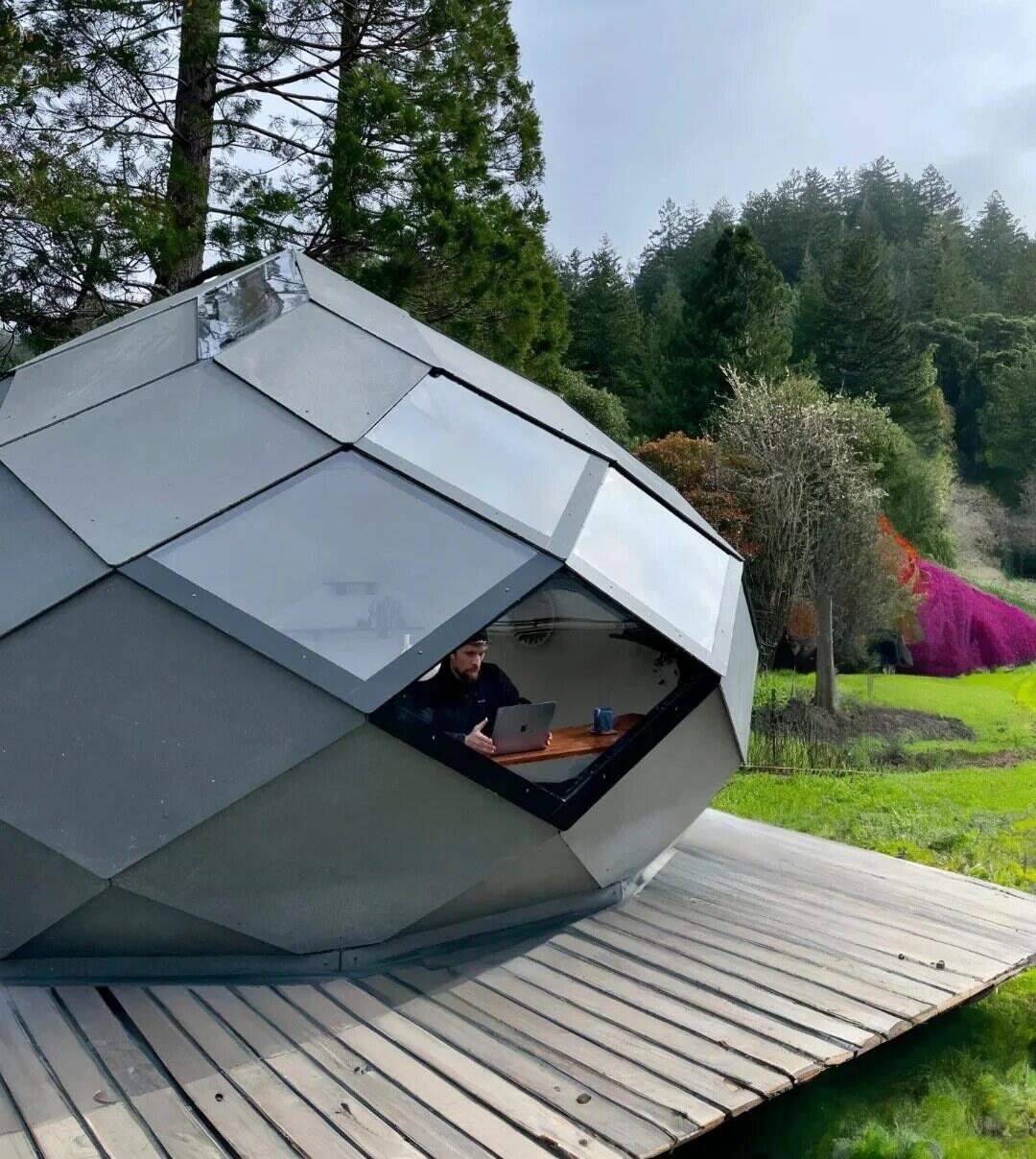 Faceted hexagonal pod on a wooden deck among the trees